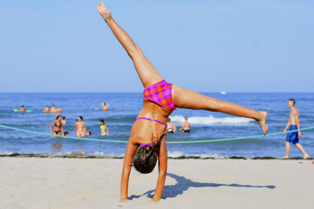 Una bambina fa la ruota in spiaggia